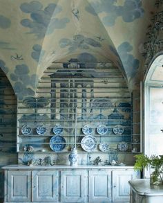 an old kitchen with blue and white wallpaper, cabinets and plates on the shelves