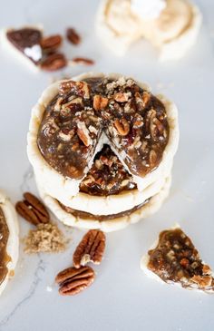 several pecan pies are arranged on top of each other with nuts scattered around them