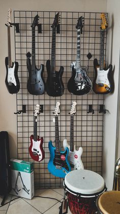 several guitars are hanging on the wall in front of a drum and other musical instruments