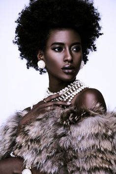 a woman with an afro and pearls on her neck, wearing a fur stoler