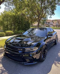 a black dodge charger is parked on the street