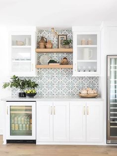 a kitchen with white cabinets and tile backsplashing on the wall above it