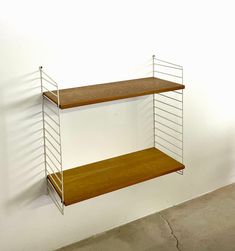 a wooden shelf with two metal shelves on the top and bottom, against a white wall