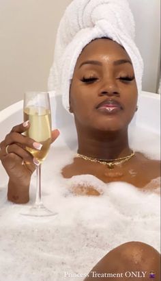 a woman sitting in a bathtub holding a glass of wine