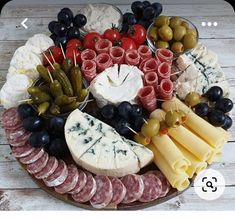 a platter filled with different types of cheeses, meats and olives