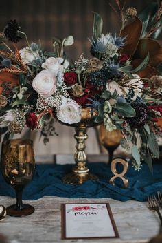 a table topped with a gold vase filled with flowers