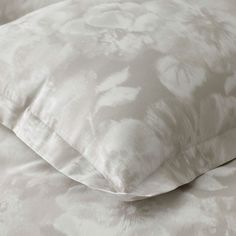 a white pillow sitting on top of a bed next to a light colored comforter