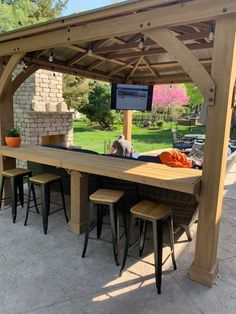 an outdoor bar with stools and tables under a pergolated roof in a backyard