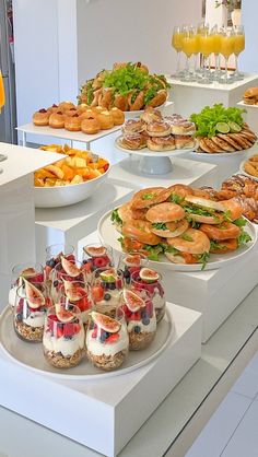 an assortment of food on display at a buffet table with glasses of orange juice in the background