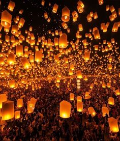 many people are flying lanterns in the sky at night with their hands up and there is no image to describe