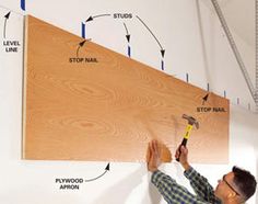 a man holding a hammer in front of a wooden wall with instructions on how to use it