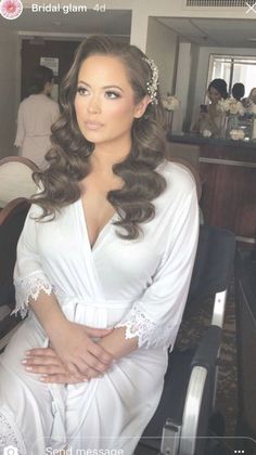 a woman in white robe sitting on a chair with her hands on her hips and looking at the camera