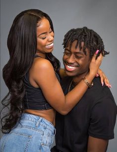 a man and woman hugging each other in front of a gray background