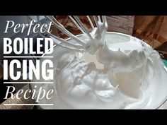 a white bowl filled with whipped cream and a whisk on top of it