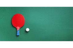 a ping pong paddle and ball on a green surface