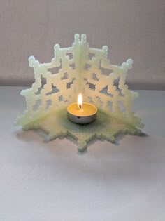 a lit candle sitting on top of a snowflake shaped object with an intricate design