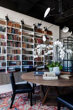 a dining room table surrounded by bookshelves and flowers