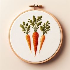 two carrots with green leaves on them are embroidered onto a white wallhanger