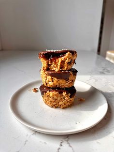 three granola bars stacked on top of each other on a white plate with chocolate drizzle