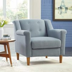 a living room with a blue chair and coffee table in front of a large window