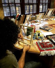 a man sitting at a table with many paintings on it