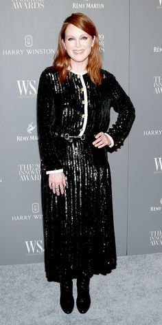 a woman standing in front of a wall wearing a black dress