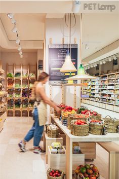 a woman walking through a grocery store filled with produce