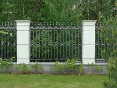 an iron fence and gate in the middle of a grassy area with trees behind it