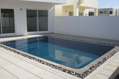 an empty swimming pool in front of a white building with glass doors and sliding windows