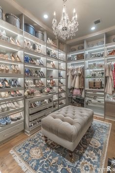 a walk in closet filled with lots of clothes and shoes on shelves next to a chandelier