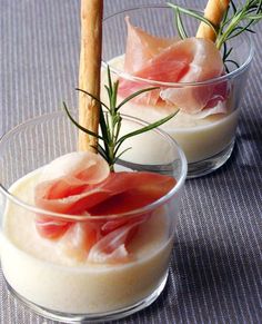 two small bowls filled with food and garnished with rosemary sprigs on top