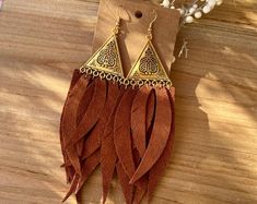 a pair of earrings with fringes on top of a wooden table