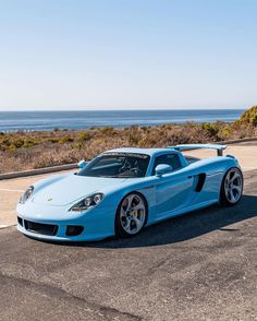 a blue sports car parked in front of the ocean