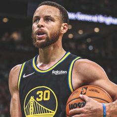 a man holding a basketball in his right hand and wearing a jersey with the golden state warriors on it