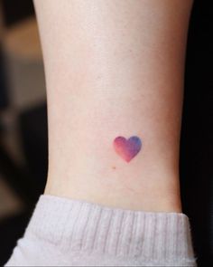 a small heart tattoo on the left side of the ankle, with pink and blue watercolors