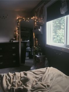 a bedroom with lights strung from the ceiling and a bed in front of a window