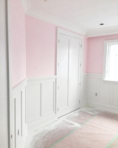 an empty room with pink walls and white trim