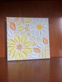 a white and yellow flower painted on top of a wooden table