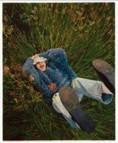 a person laying in the grass with their feet up and mouth wide open, laughing