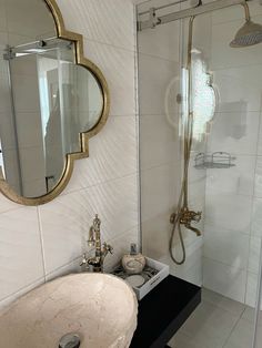 a bathroom with a sink, mirror and shower stall in the corner is white tile