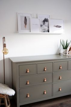 a dresser with drawers and pictures on the wall