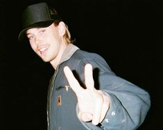 a man in a black hat making the peace sign