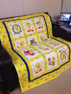 a couch with a yellow quilt on it in front of a computer desk and chair