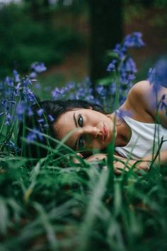 a woman laying in the grass with blue flowers