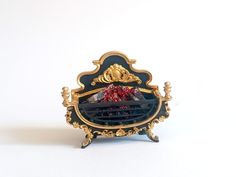 an ornate black and gold clock with red flowers on it's face, against a white background