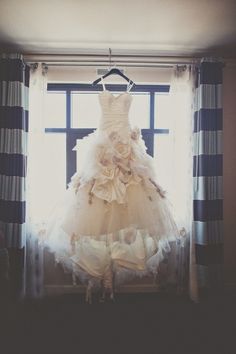 a wedding dress hanging in front of a window