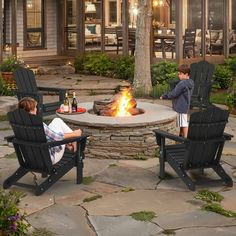 two boys sitting in chairs around a fire pit