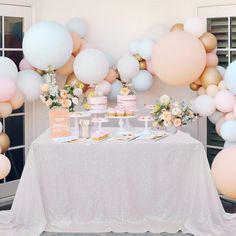 a table topped with cakes and desserts next to balloons