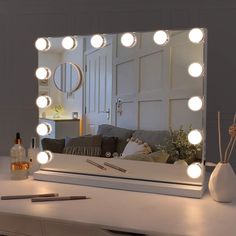 a white table with a mirror and some lights on it, in front of a couch