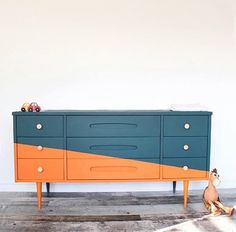 an orange and blue dresser sitting on top of a wooden floor next to a stuffed animal